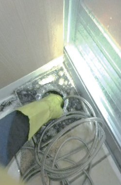 バスルームの排水管にホースを入れて洗浄している弊社スタッフ