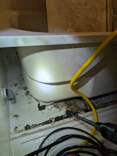 バスタブ下をホースとノズルで洗浄中